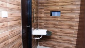 A bathroom with wooden panel walls, a white sink, and a purple rug on the floor. - Negasi Dormitory (Mumbai)