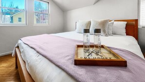 Ein Schlafzimmer mit Bett, Fenster und Tablett mit zwei Flaschen.