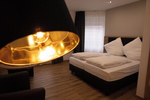 A hotel room with a bed, a large lamp, and a window with curtains. - HLN APARTMENTS (Saarbrücken)