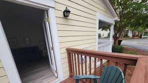 A wooden deck with a green Adirondack chair, a small table, and a white railing. - The family -friendly resort life is waiting for you! 
 (Williamsburg)
