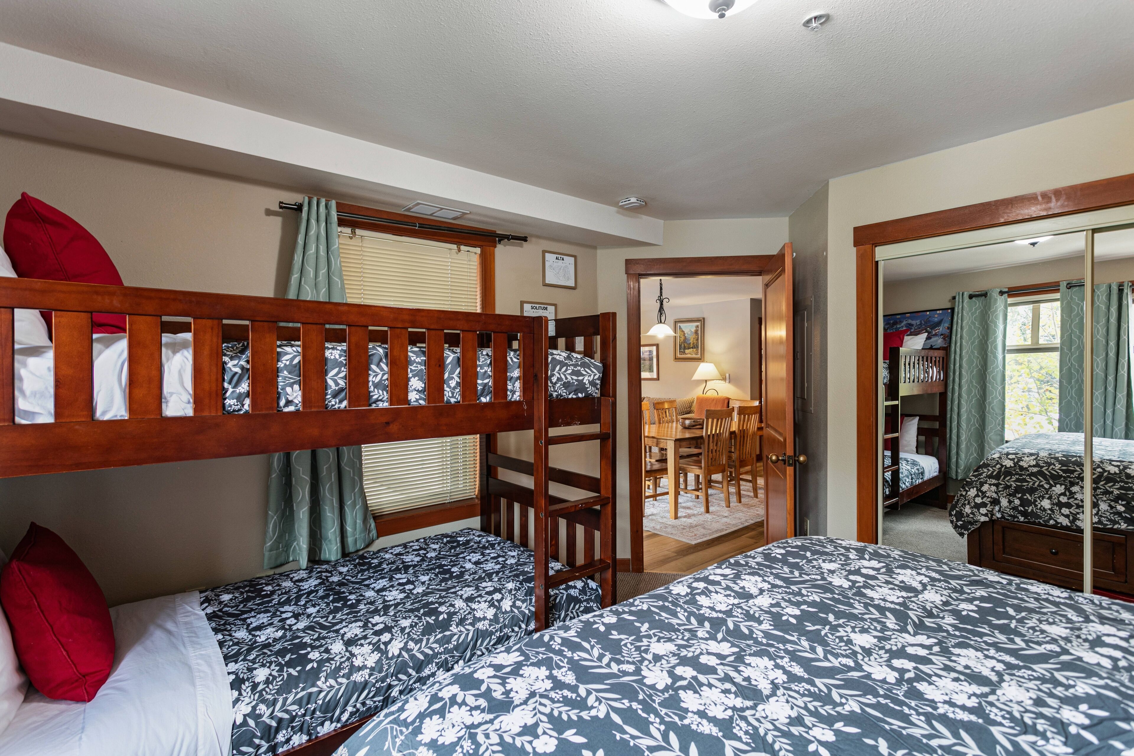 A bedroom with bunk beds, a desk, and a mirror.