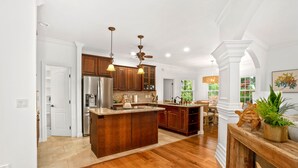 A spacious kitchen with wooden cabinets, a large island, and pendant lighting. - Kauai Wainani Villa 2 Bedroom Home (Koloa)