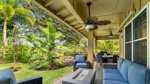 A covered outdoor seating area with wicker furniture, a fire feature, and lush tropical plants. - Kauai Wainani Villa 2 Bedroom Home (Koloa)