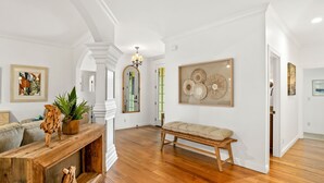 A spacious living room with hardwood flooring, a wooden coffee table, a bench, and a fireplace. - Kauai Wainani Villa 2 Bedroom Home (Koloa)