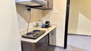 A compact kitchenette with a stove, sink, and coffee maker. - Orchida Al Hamra (Riyadh)