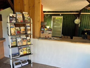 A reception area with a wooden reception desk, a clock, and a display of travel magazines and brochures. - Hameau des laurières (Saint-Avit-Senieur)