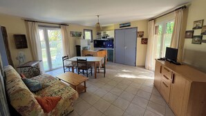 Espai vital compacte amb sofà, taula de dinar, zona de cuina i televisió sobre un moble.