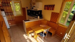 Cuina compacta amb taula de fusta, una banca integrada i un microones.