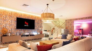 Un soggiorno moderno con una grande TV a schermo piatto, una scala e un'area reception.