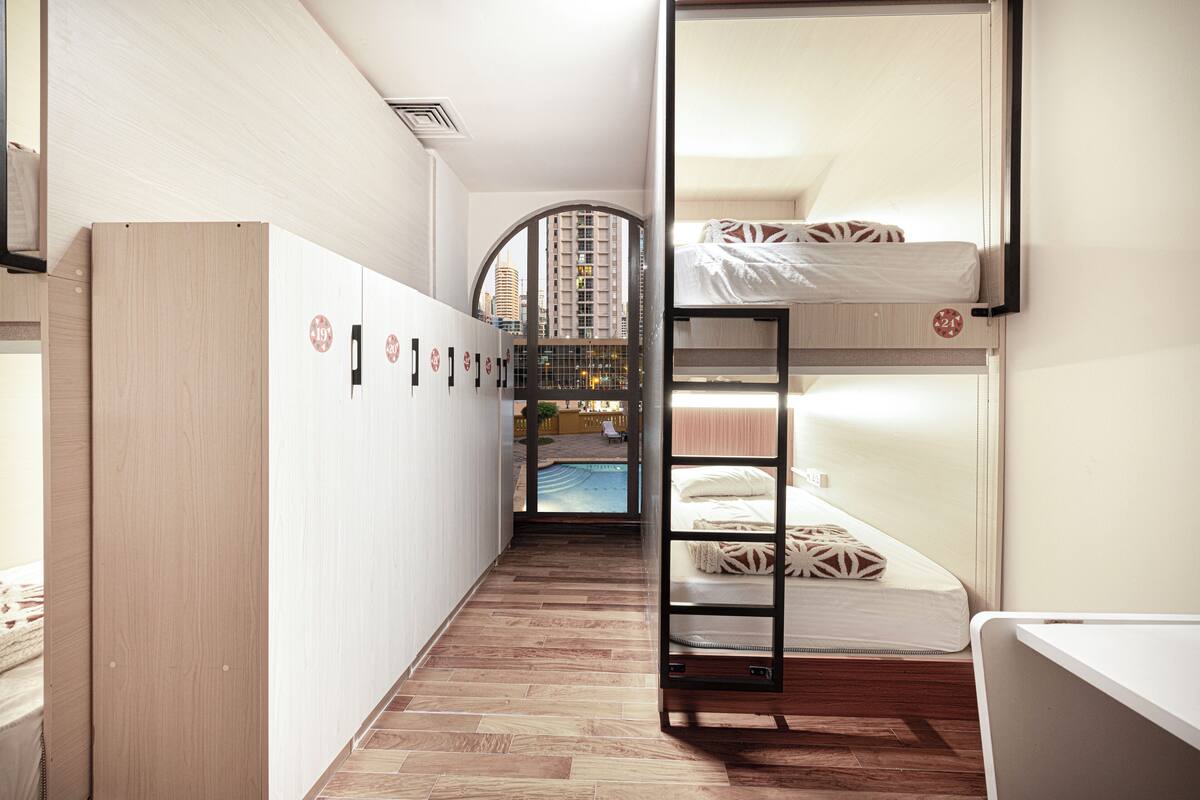 A bunk bed room with a view of a building and a pool.