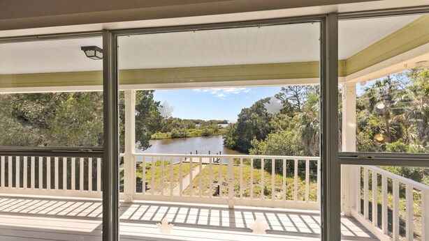 Un balcon fermé offrant une vue sur une rivière et la végétation environnante.