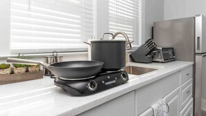 Una cocina moderna con una cocina de inducción portátil, una sartén, una olla y un tostador.