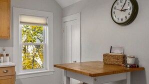 Une cuisine avec une fenêtre, une horloge, une table et un panier.