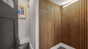 Une salle de bain moderne avec un mur recouvert de lambris en bois, une porte dotée d’une poignée métallique et une affiche accrochée au mur.