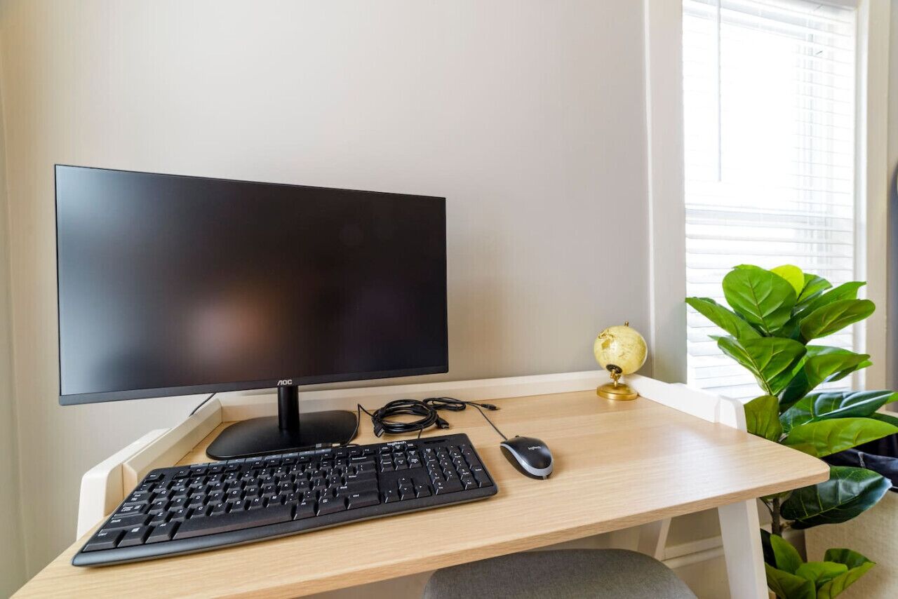 Een computerbureau met een monitor, toetsenbord en muis.