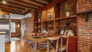 Un comedor rústico con mesas y sillas de madera, paredes de ladrillo y estantes con adornos.