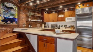 Una cocina con armarios de madera, un refrigerador de acero inoxidable y un ventanal con vitrales.