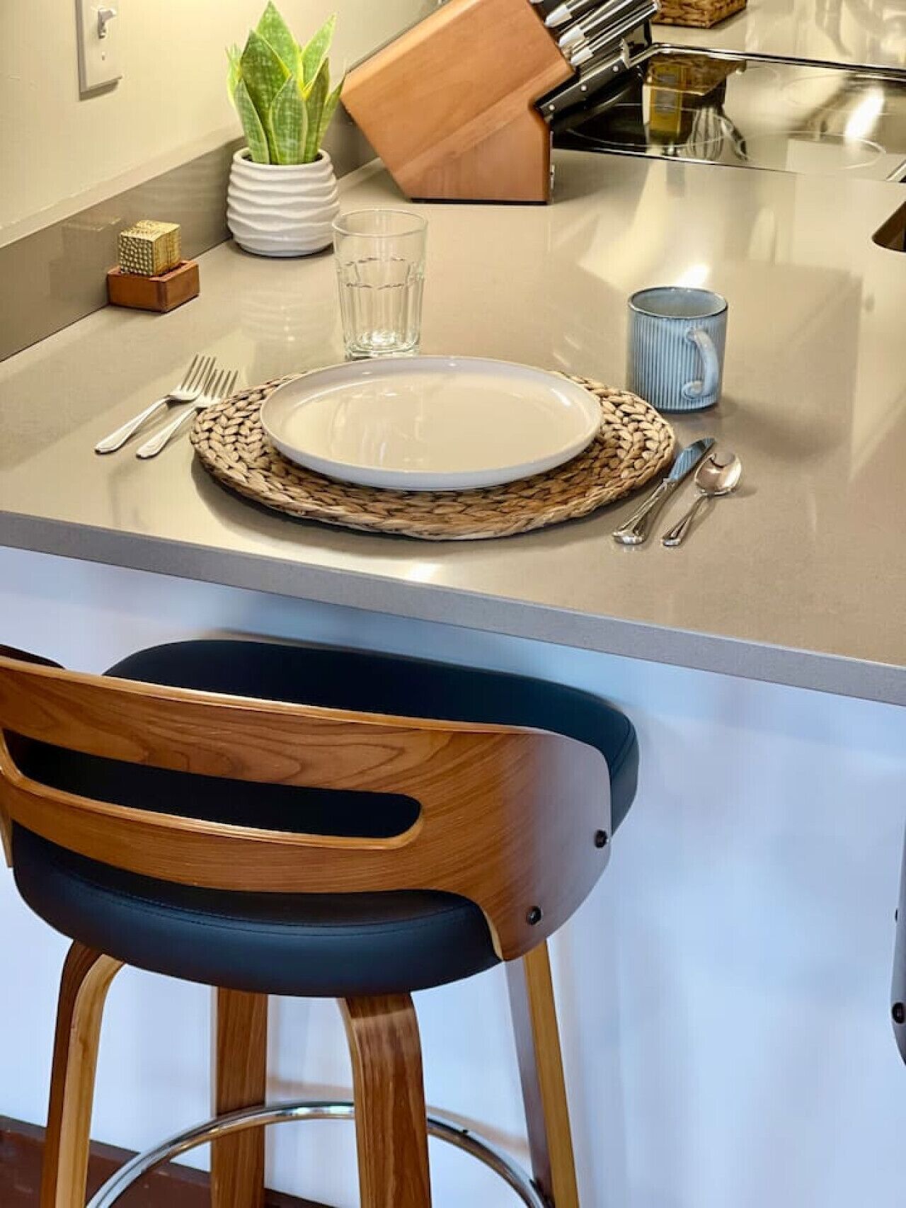 Un plan de travail de cuisine avec une assiette, des couverts, un verre, une tasse et un bloc à couteaux.