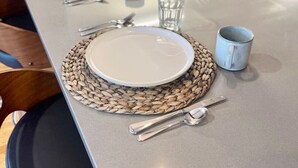 Una mesa con platos, cubiertos y un camino de mesa tejido.