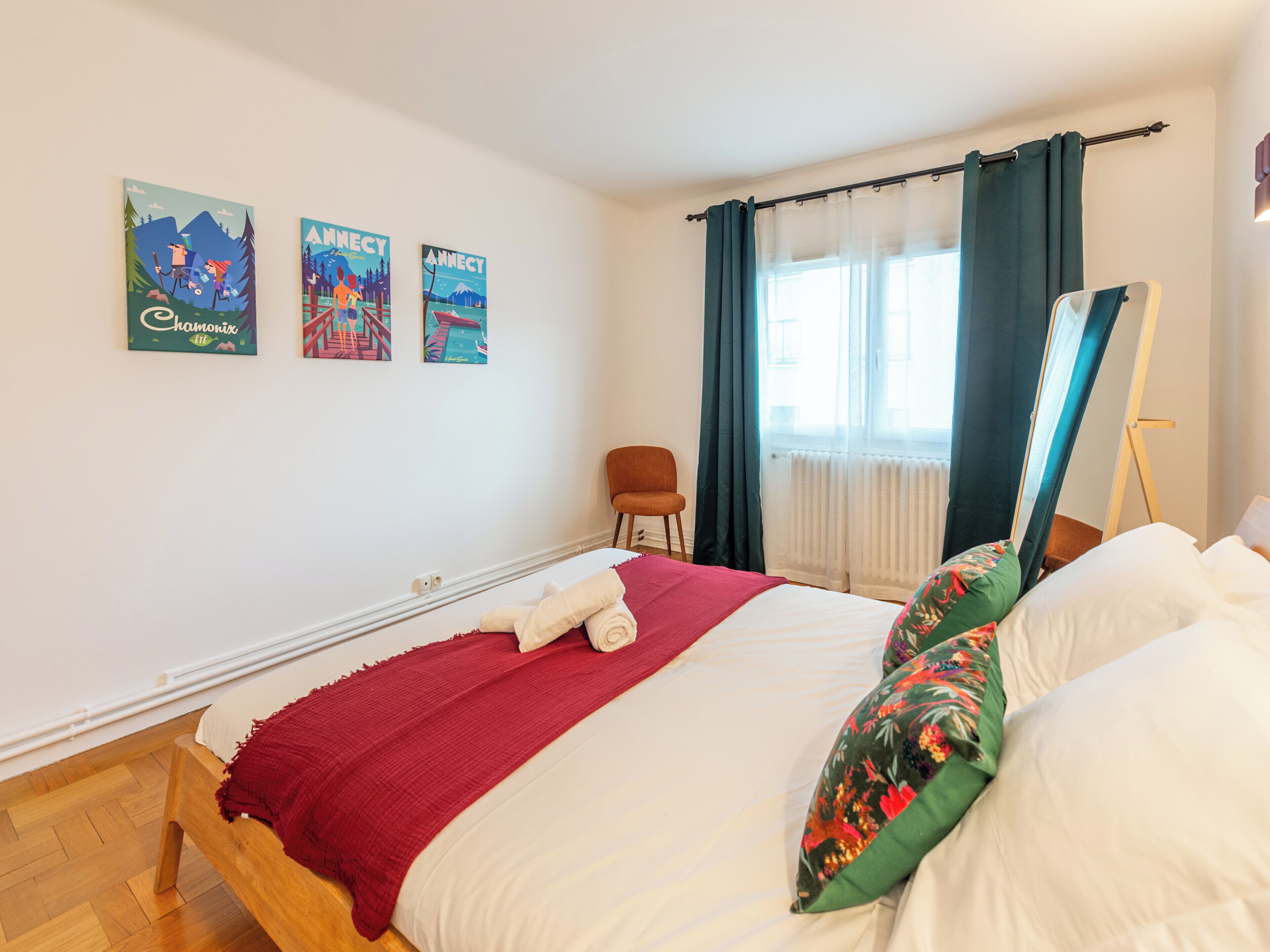 A bedroom with a bed, a chair, a window with curtains, and three wall posters.