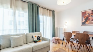 En moderne stue med sofa, skammel, spisebord, stole og en lampe.