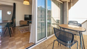 En balkon med skydedør, et træbord og to stole.