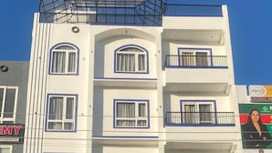 A multi-story hotel with balconies and a restaurant named "AURA" on the ground floor. - Hotel Aura By Arihant (Udaipur)