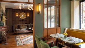 A cozy interior with wooden floors, a patterned rug, a green upholstered bench, and a glass display case. - Les Rives Oceanik (Paris)