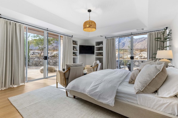 Une chambre à coucher avec un lit, une télévision, une chaise et une vue sur l’extérieur.