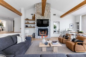 Una sala de estar moderna con chimenea de piedra, televisor de pantalla plana y asientos cómodos.