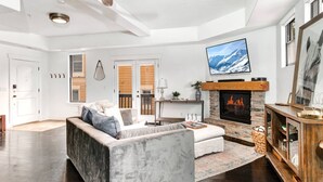 A modern living room with a stone fireplace, a large flat-screen TV, and a cozy seating area.
