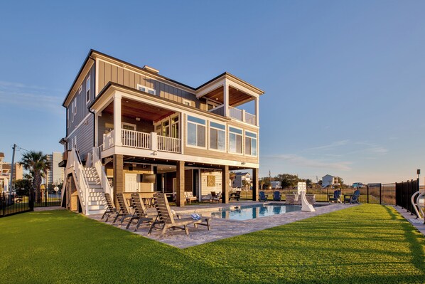 A two-story house with a balcony, a swimming pool, and a well-maintained lawn.