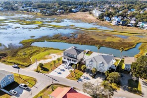 A residential area with a large house featuring a spacious front yard, a driveway, and a view of a water body.