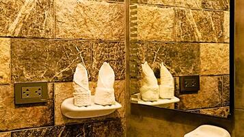 A bathroom with a stone wall, a sink, and two towel dispensers.