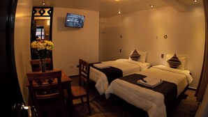 Ett hotellrum med två sängar, ett skrivbord, en stol och en tv på väggen.
