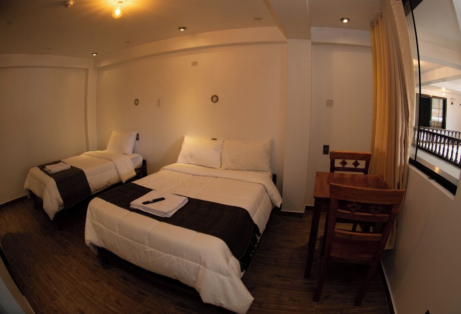 A hotel room with two beds, a wooden chair, and a small table.