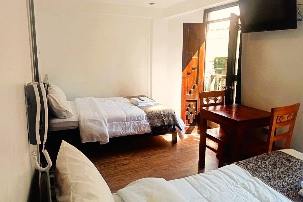 A room with two beds, a wooden desk, and a chair.
