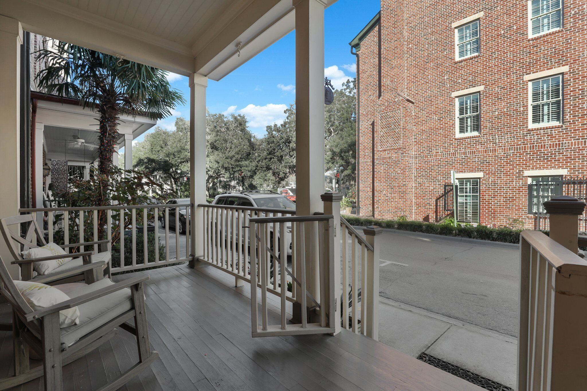 A covered porch with a wooden bench, a brick building with windows, and a street view.