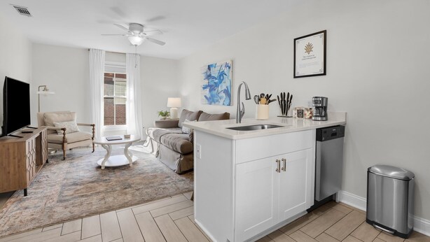 A modern kitchen with white cabinetry, a built-in dishwasher, and a stainless steel sink.