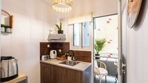 A compact kitchen with a sink, toaster, kettle, and potted plants. - Elena's Cozy & Central Nest (Kalamata)