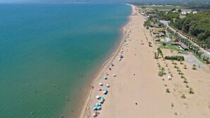 An aerial view of a beach with a long stretch of sand, a few umbrellas, and a few people. - Aelia Guesthouse - Private Garden Retreat (Daras)