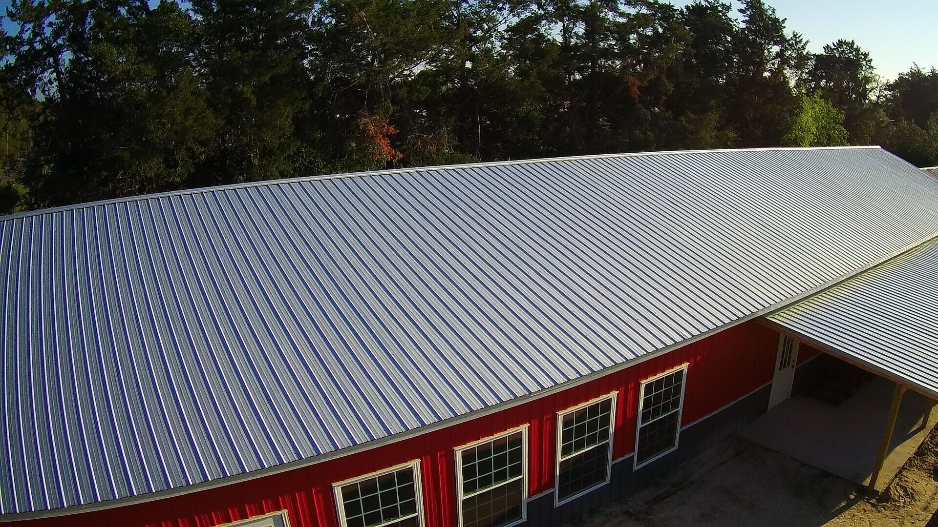 A red building with a corrugated metal roof and multiple windows.