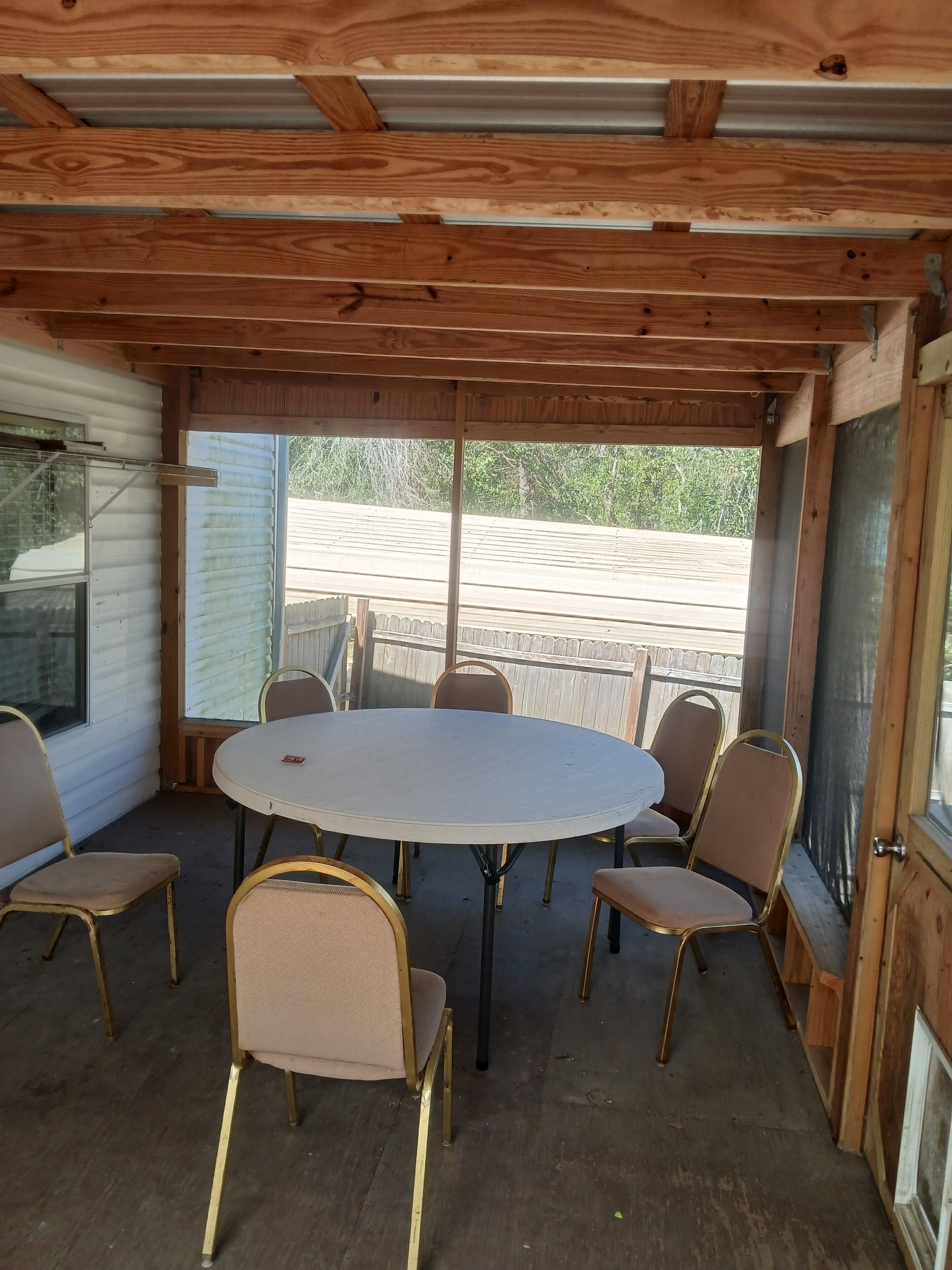 Un patio techado al aire libre con una mesa redonda y seis sillas.
