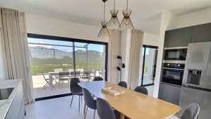 Una cocina moderna con horno integrado y comedor con mesa y sillas.