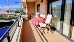 Un balcón con mesa y sillas, una piscina y vistas a grúas de construcción.