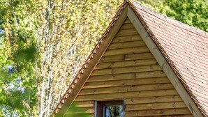 Une cabane en bois avec un toit à pignon et une petite fenêtre.