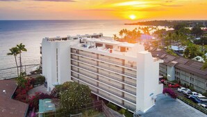 Un hôtel à plusieurs étages offrant une vue sur l’océan au coucher du soleil.