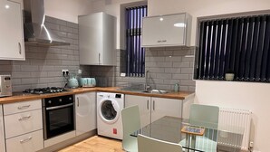 A modern kitchen with a washing machine, a stove, and a sink. - Lux Modern Apartment in Nuneaton (Nuneaton)