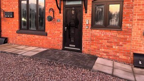A red brick building with a black door, two windows, and a mailbox. - Lux Modern Apartment in Nuneaton (Nuneaton)