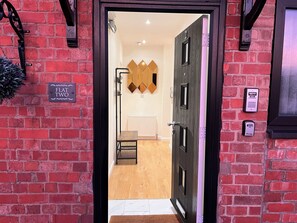 A hotel entrance with a brick wall, a sign reading "FLAT TWO", and a door with a keypad lock. - Lux Modern Apartment in Nuneaton (Nuneaton)